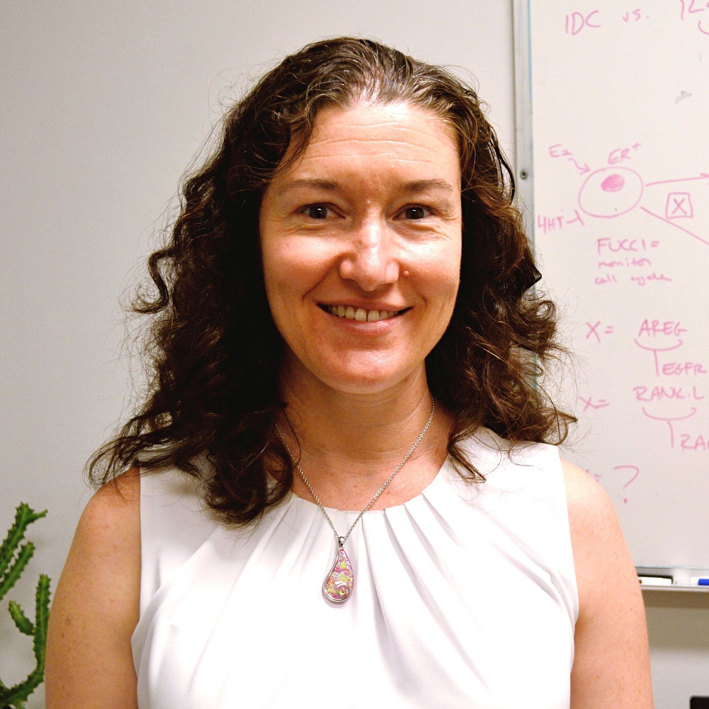 headshot of rebecca riggins in front of a whiteboard.