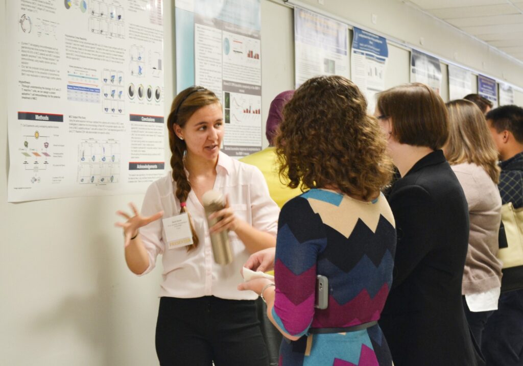 Student Research Day 2017 attendees talk in front of a research poster