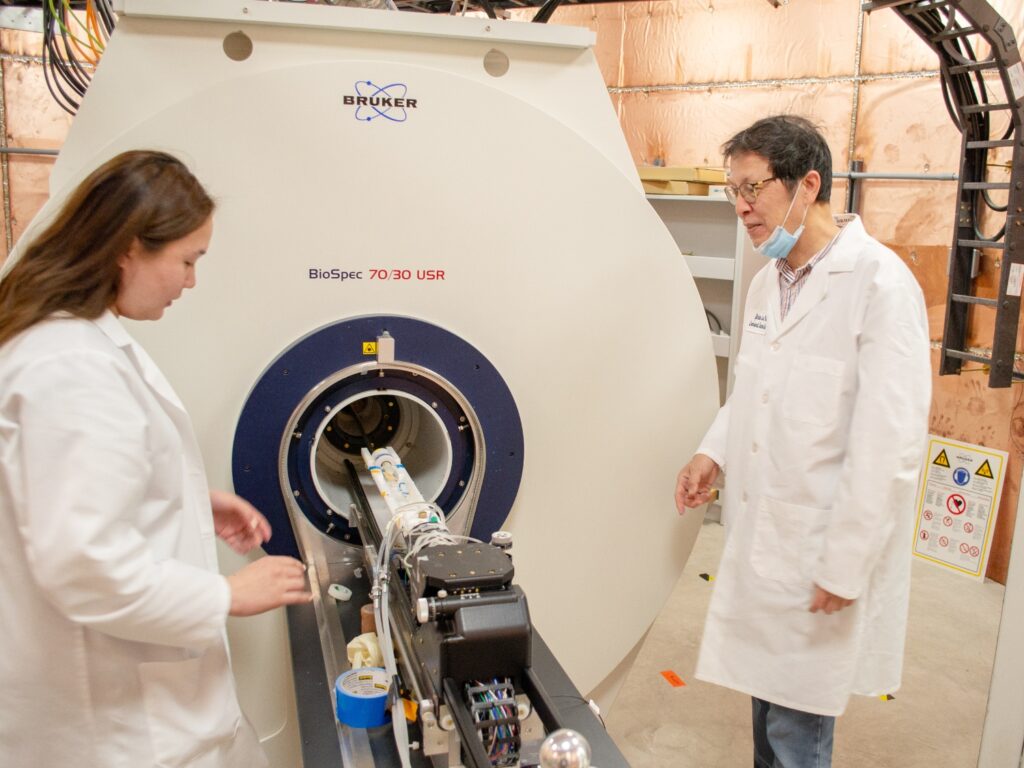 A doctoral student and professor work with an MRI machine.