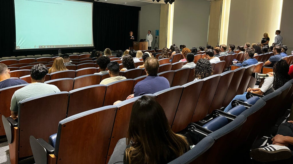 New students in the Special Master's Program in Physiology & Biophysics, GUMC Cohort, listen to Assistant Director Amy Richards in an auditorium during orientation.