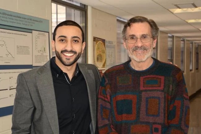 Barry Wolfe stands with a Pharmacology master's student in front of posters.