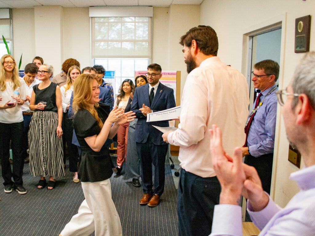 The third-place award winner accepts her award at the Pharmacology and Physiology poster session