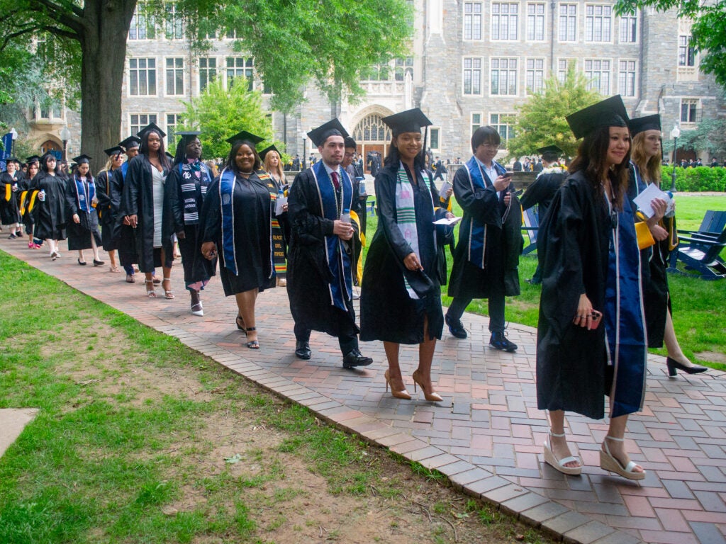 Graduates process across Copley Lawn at Commencement