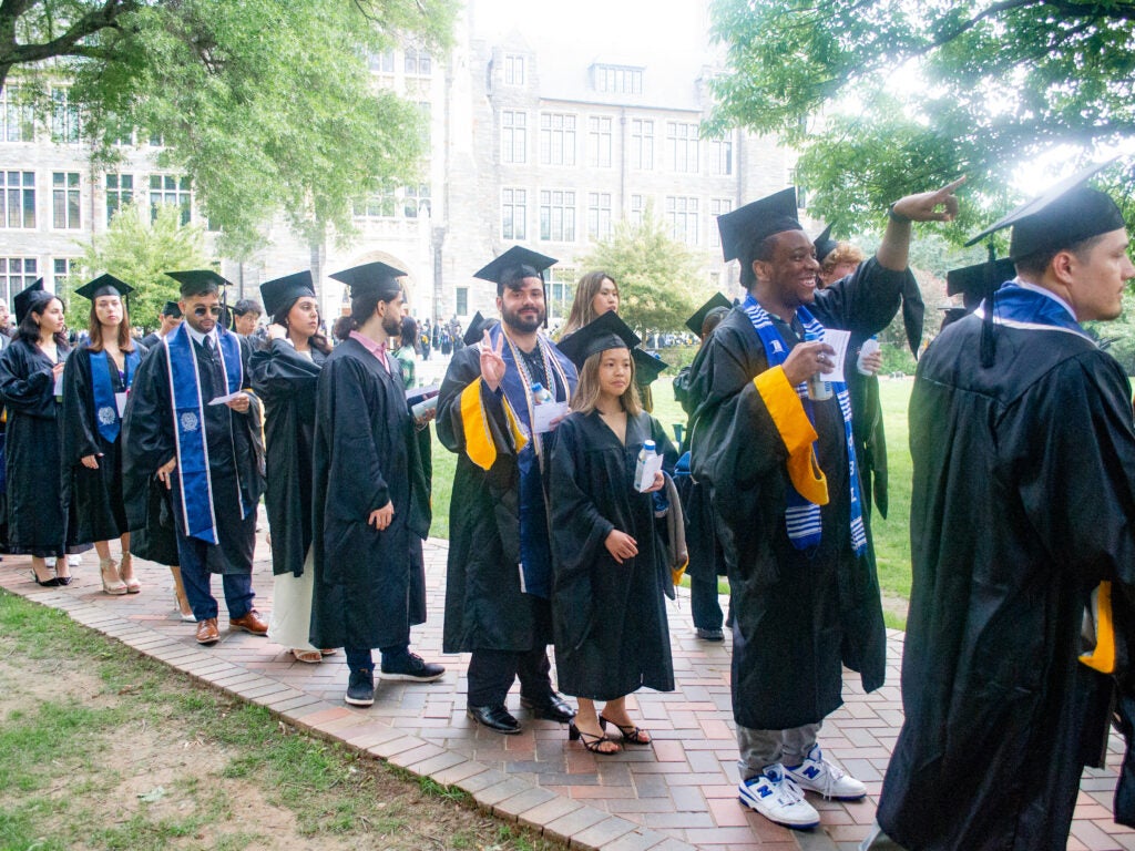 Graduates process across Copley Lawn at Commencement