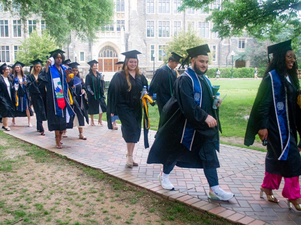 Graduates process across Copley Lawn at Commencement