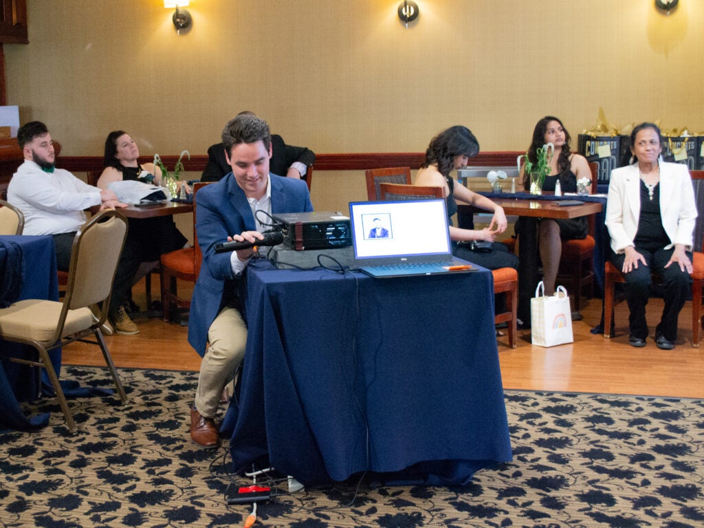 A student holds the microphone up to amplify a video soundtrack at the Systems Medicine program gala
