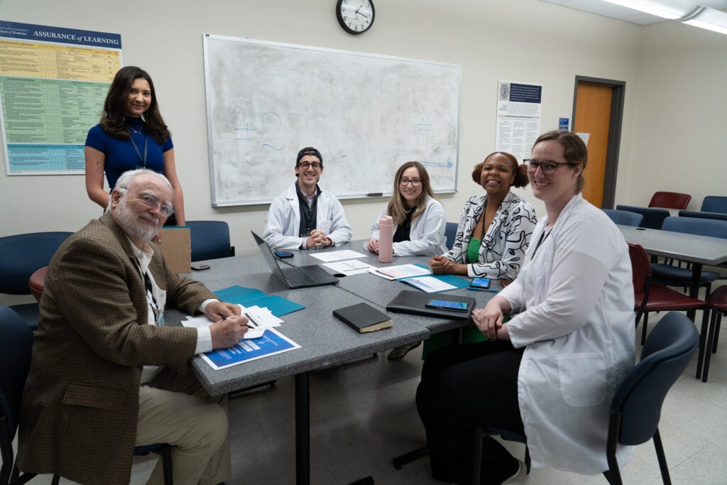 A group of people assigned as health professionals smile and pose for the camera