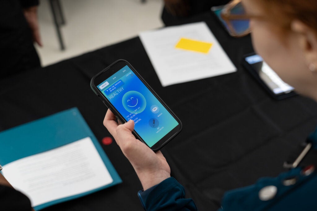 A close-up of a smartphone screen displaying the outbreak app, this participant is currently "healthy."