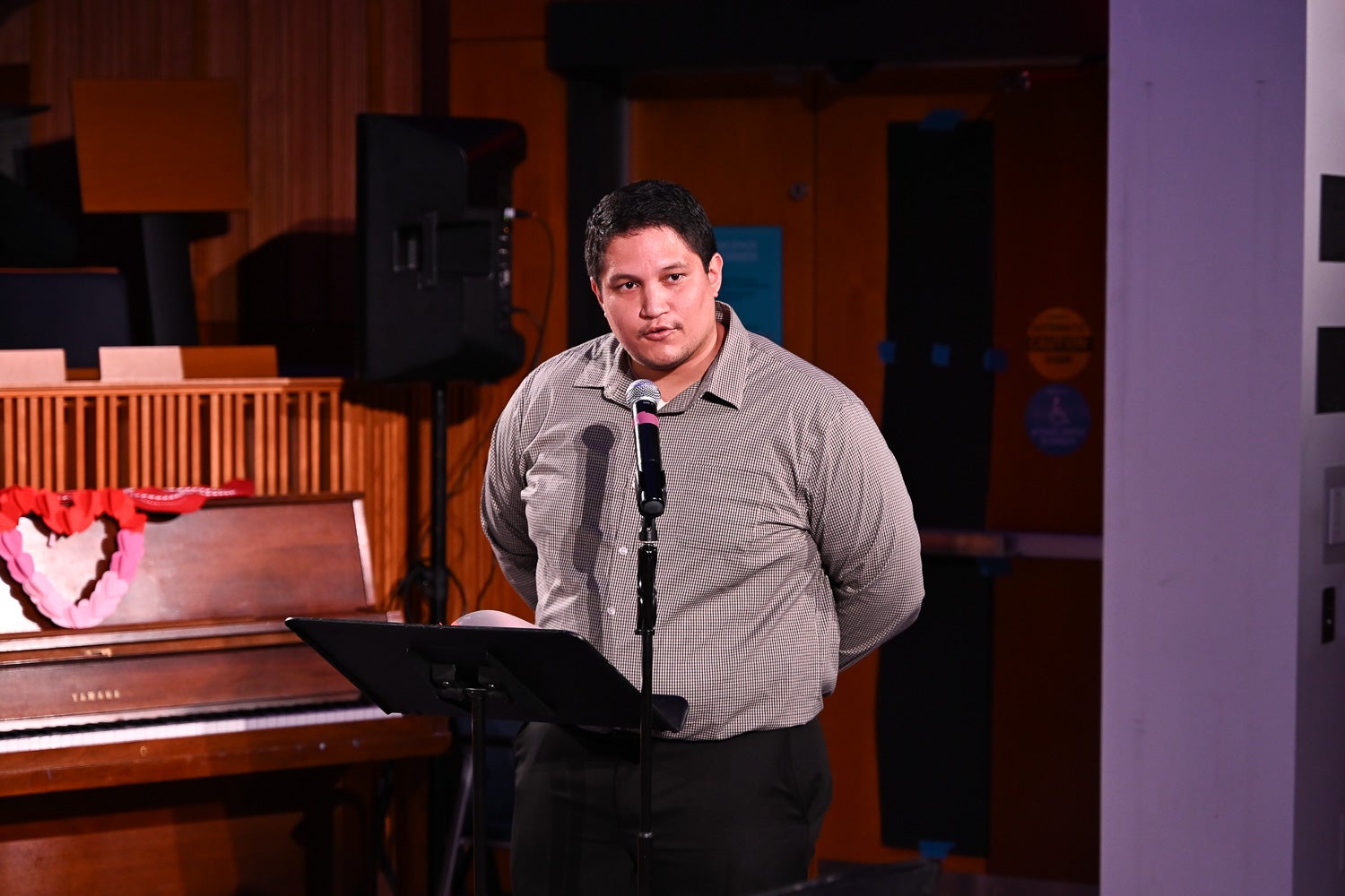Neuroscience Ph.D. student Zachary Colon stands at the microphone on the Harvey Amphitheater stage as he recites his poem