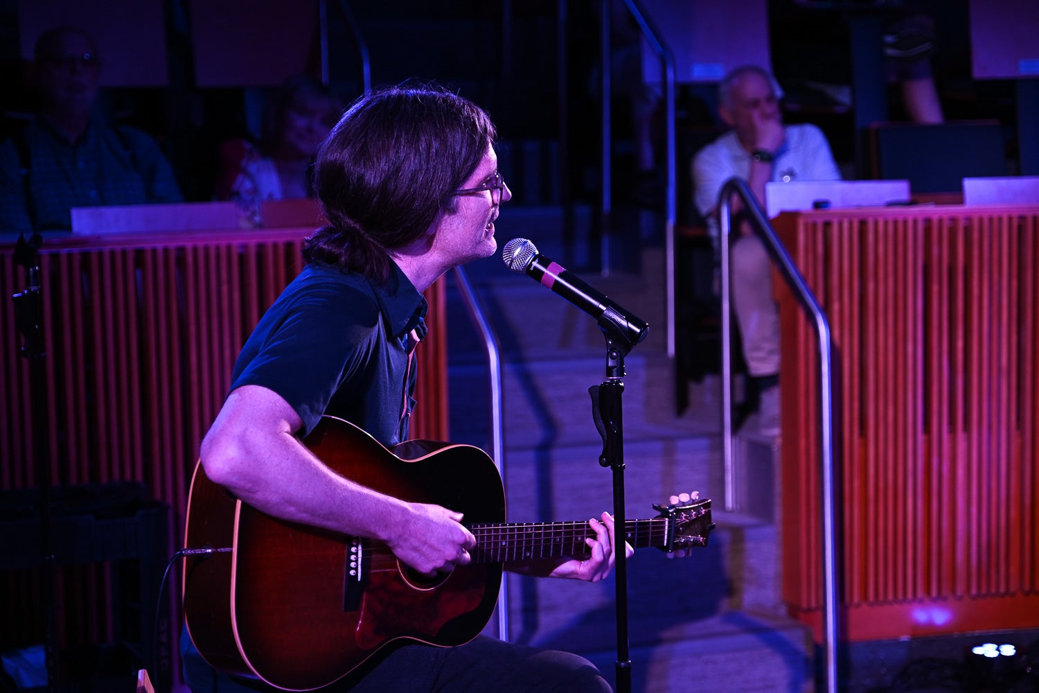 Jay Hammond, performing arts professor, sits with his guitar while singing and playing his song