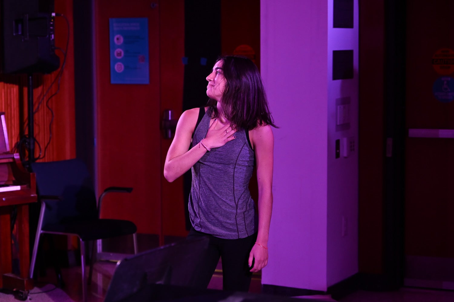 Undergraduate student Raquel Silva holds her hand over her heart while smiling at her mother from the Harvey Amphitheater stage