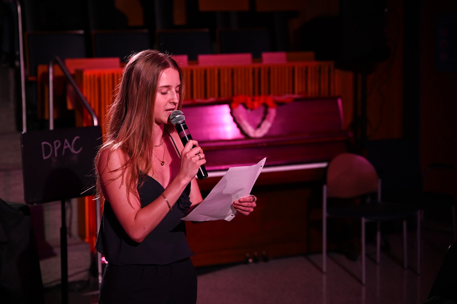 Ariadna (Arina) Maksin, undergraduate student, holds a microphone and paper while reading her poem