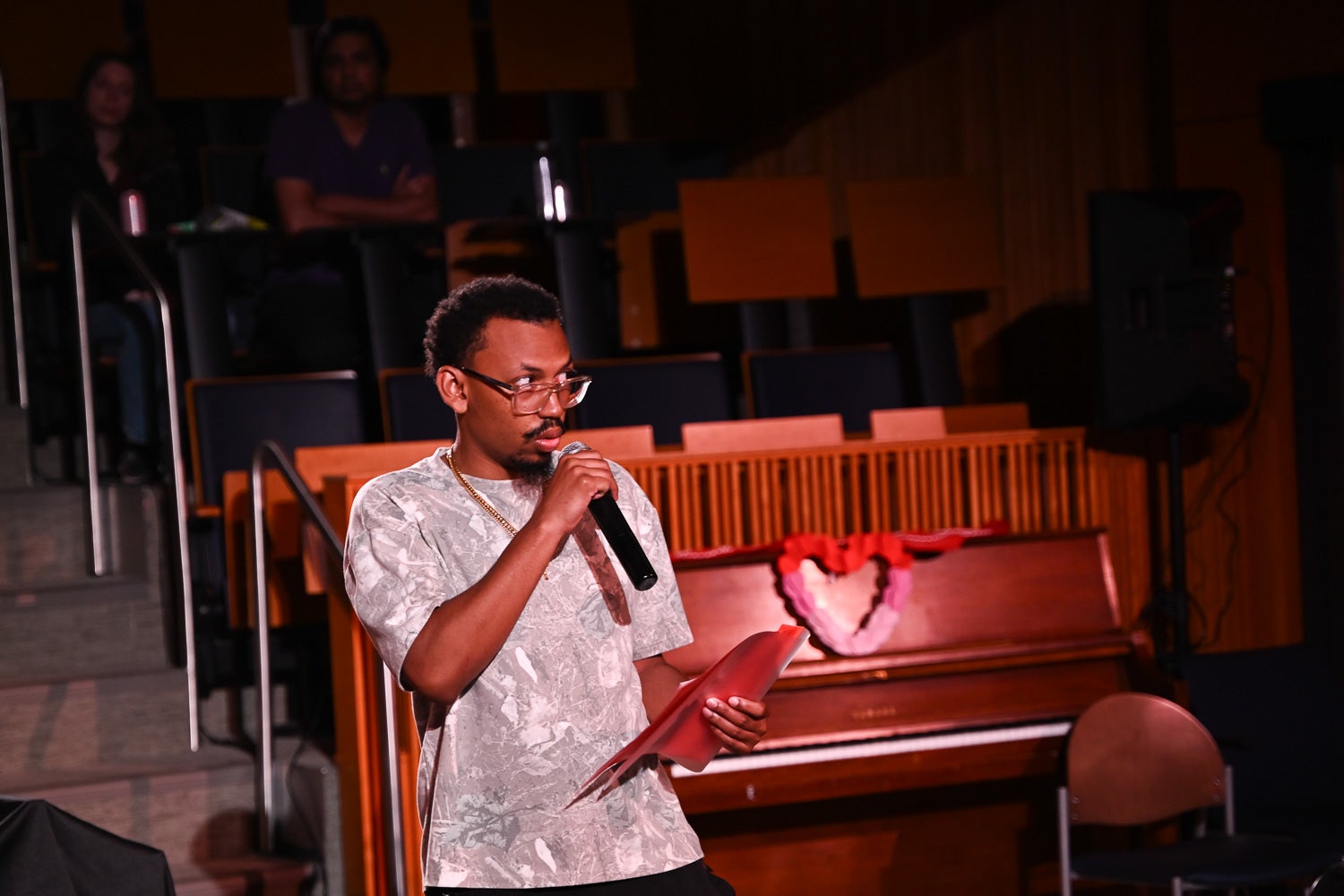 Integrative Medicine & Health Sciences master's student Kevin Williams holds a microphone and folder while reciting