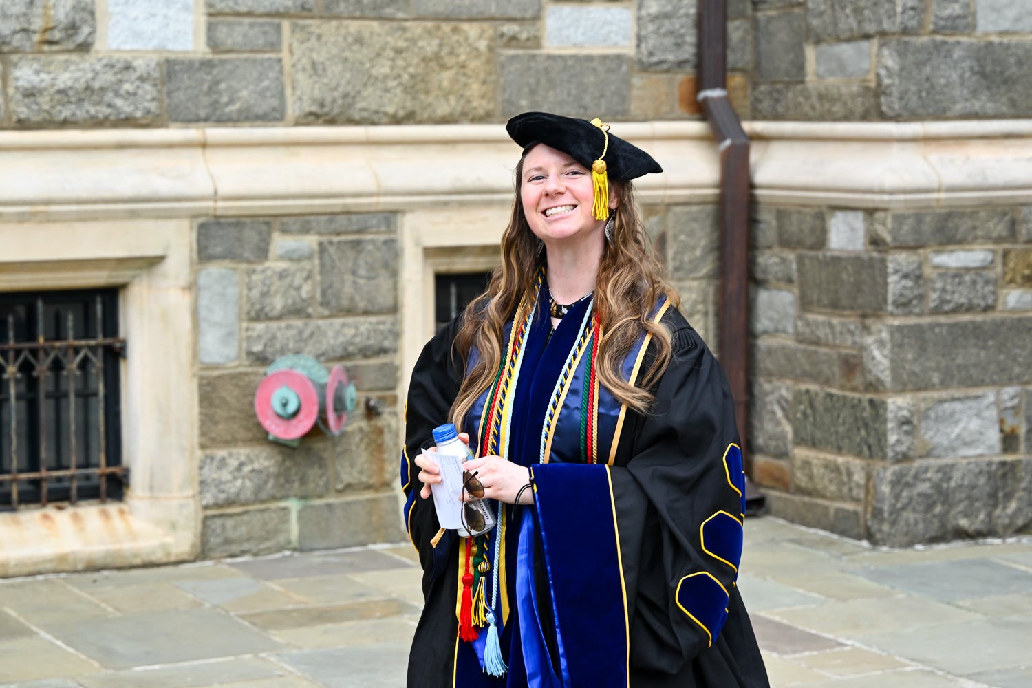 A BGE Ph.D. graduate walks on White-Gravenor Esplanade before the School of Medicine Commencement ceremony