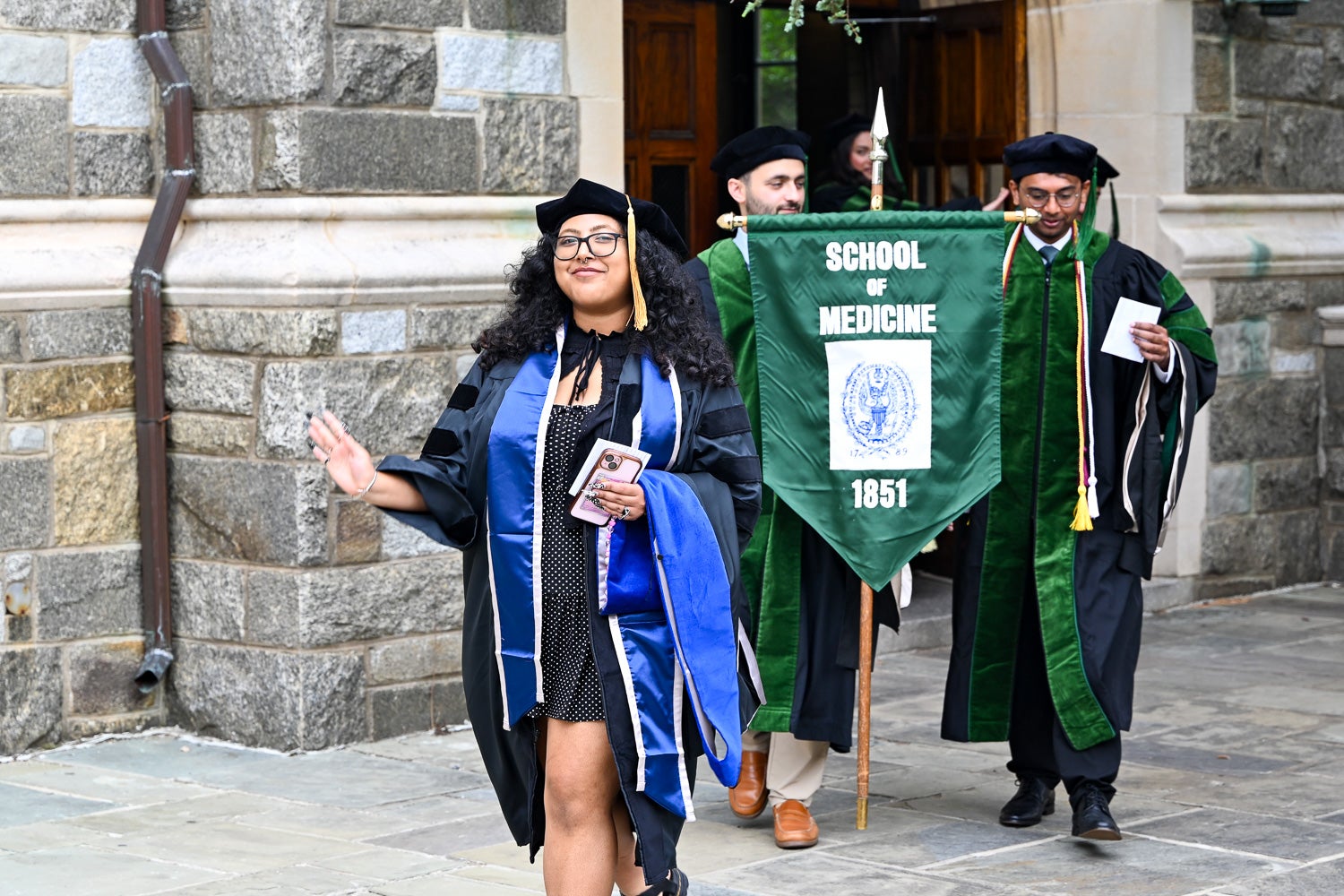 A BGE Ph.D. graduate walks on White-Gravenor Esplanade before the School of Medicine Commencement ceremony