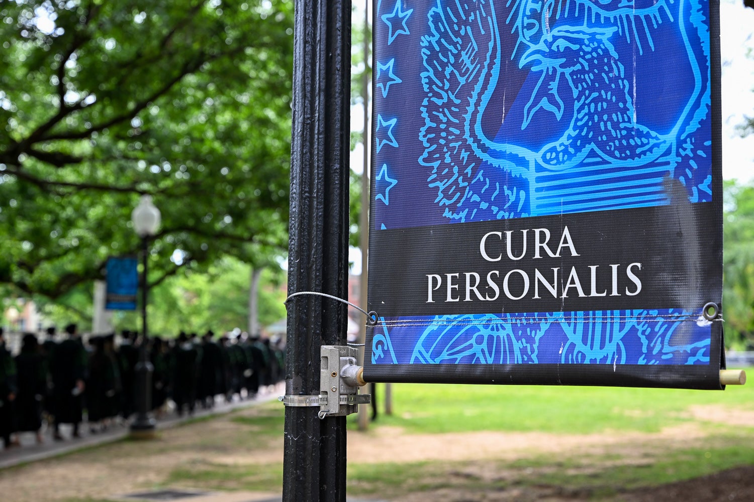 BGE Ph.D. graduates process across Copley Lawn to Healy Lawn for the School of Medicine Commencement ceremony, with a Georgetown 