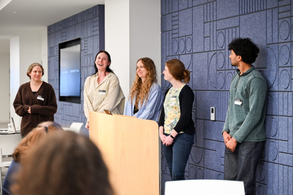A team member speaks while others and audience listen