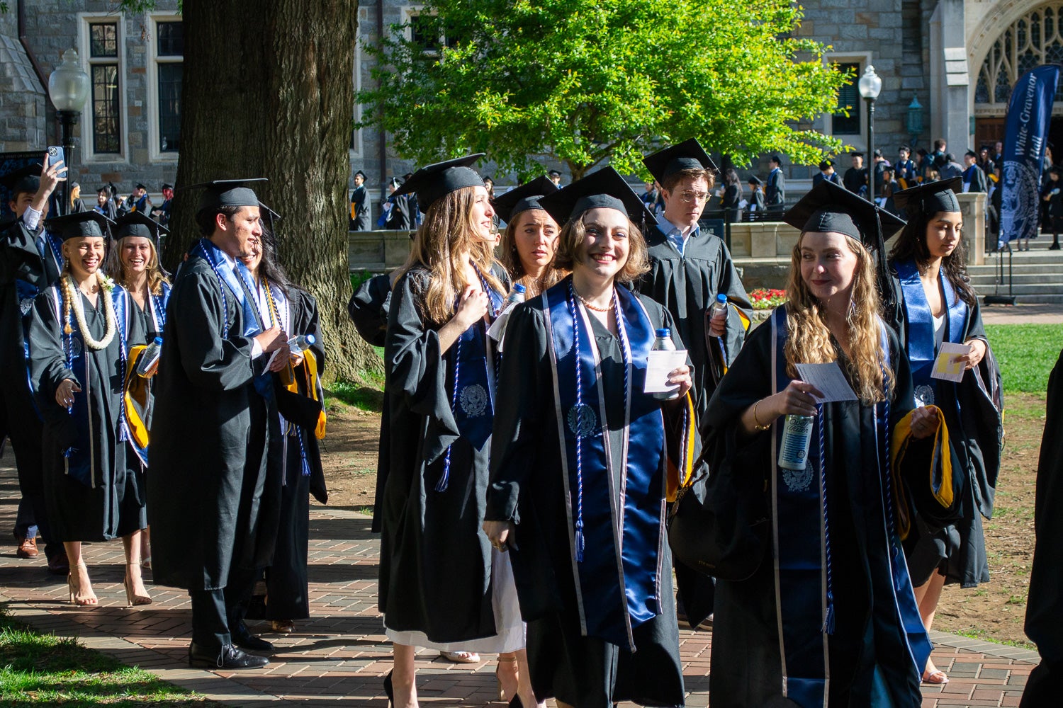 Graduates in commencement regalia process across Copley Lawn to the ceremony