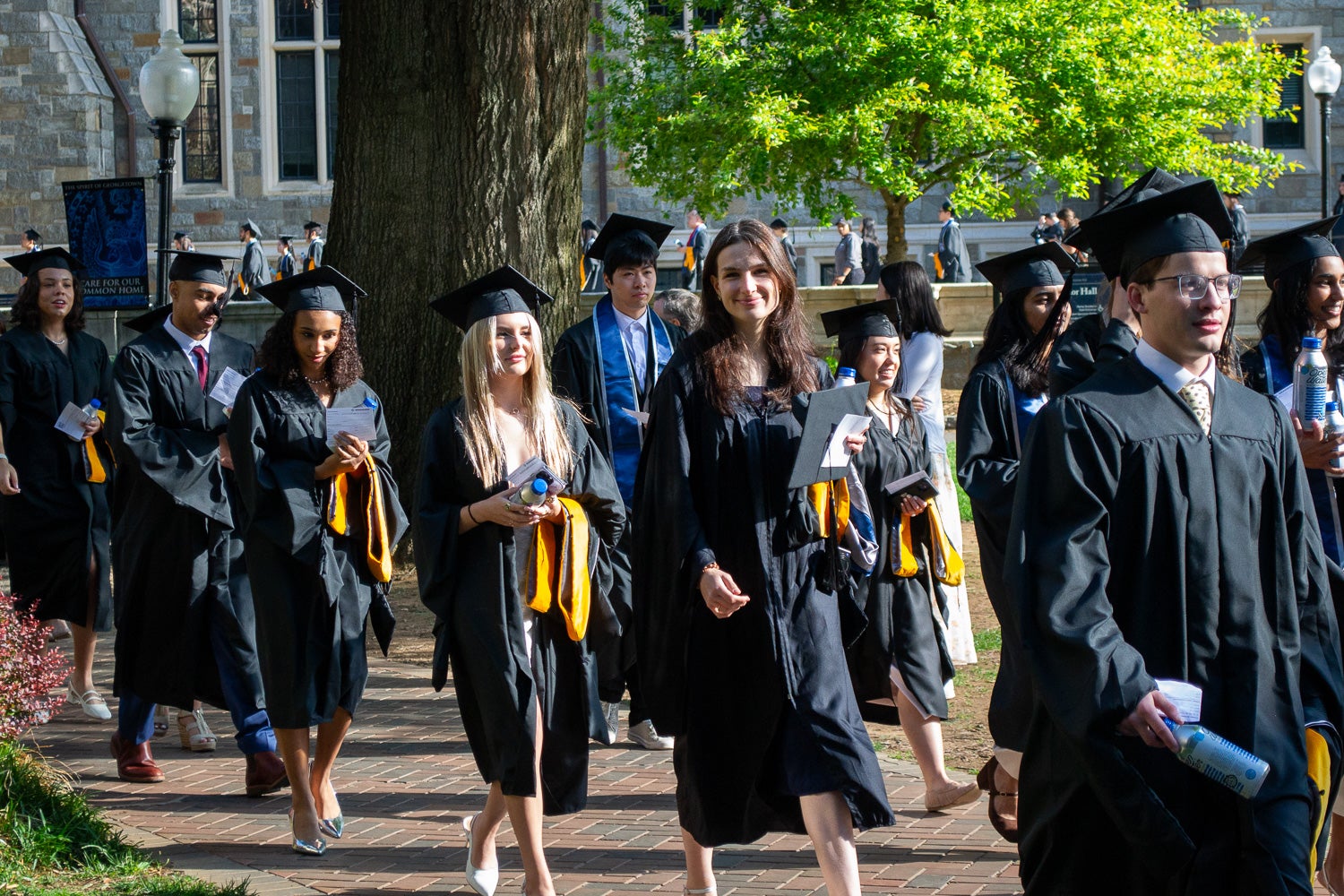 Graduates in commencement regalia process across Copley Lawn to the ceremony