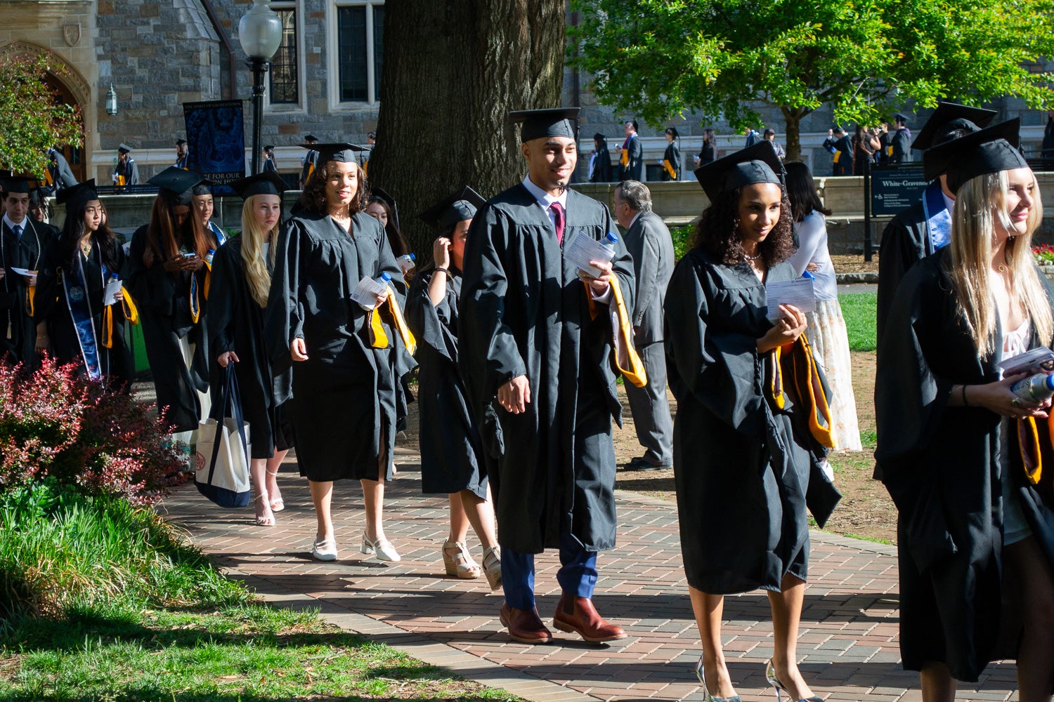 Graduates in commencement regalia process across Copley Lawn to the ceremony
