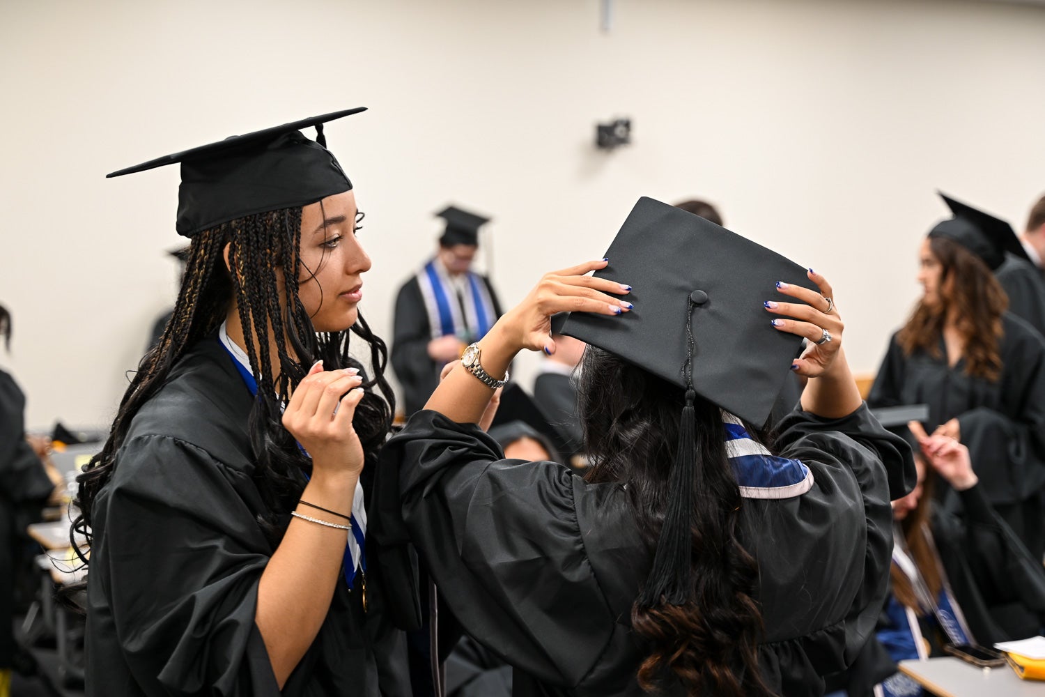 Graduates dressed in commencement regalia talk in the line-up room