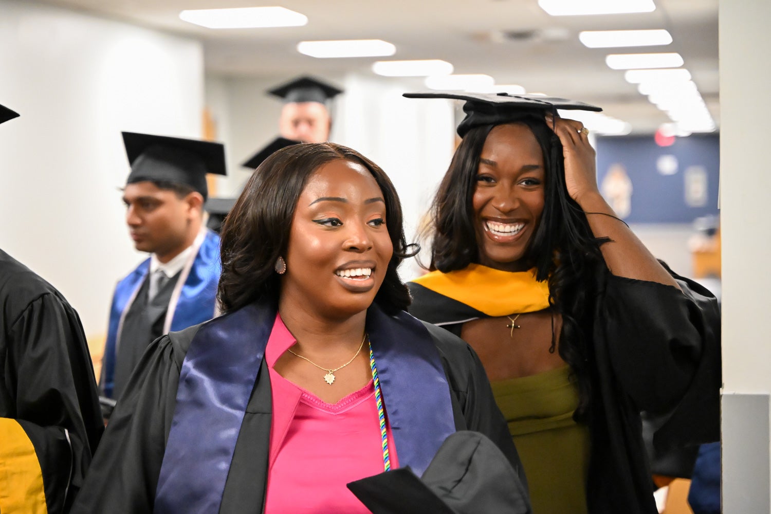 Graduates walk out of the line-up room in their commencement regalia