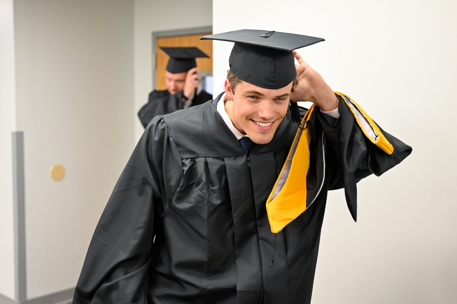 Graduates walk out of the line-up room in their commencement regalia