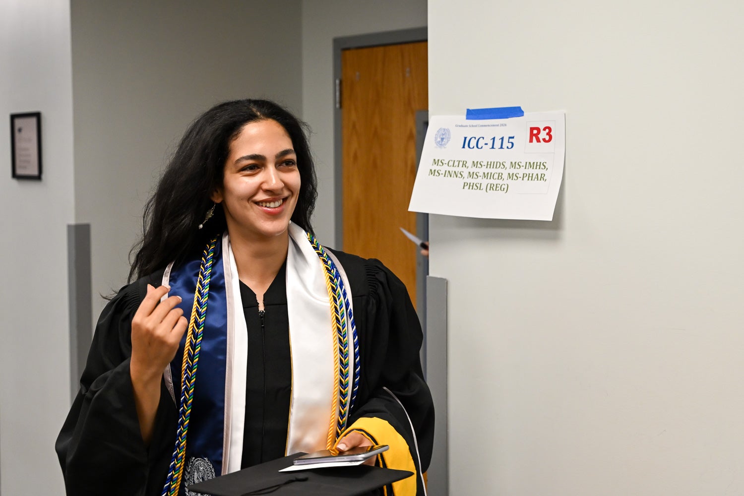 Graduates walk out of the line-up room in their commencement regalia