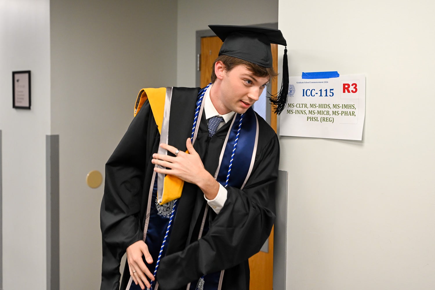 Graduates walk out of the line-up room in their commencement regalia