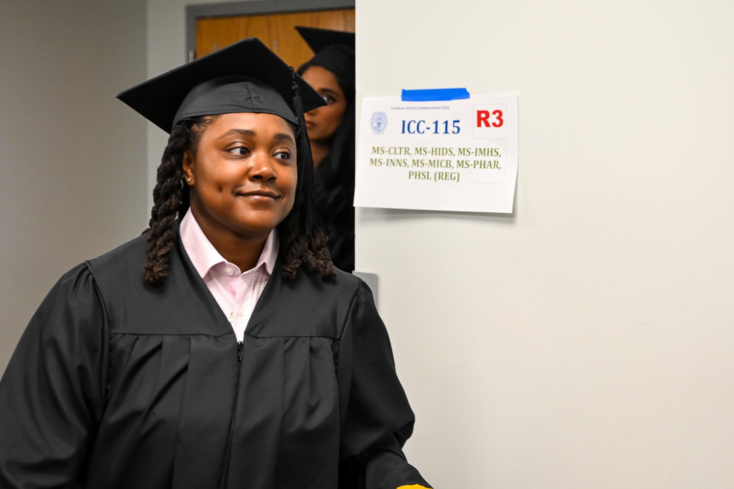 Graduates walk out of the line-up room in their commencement regalia