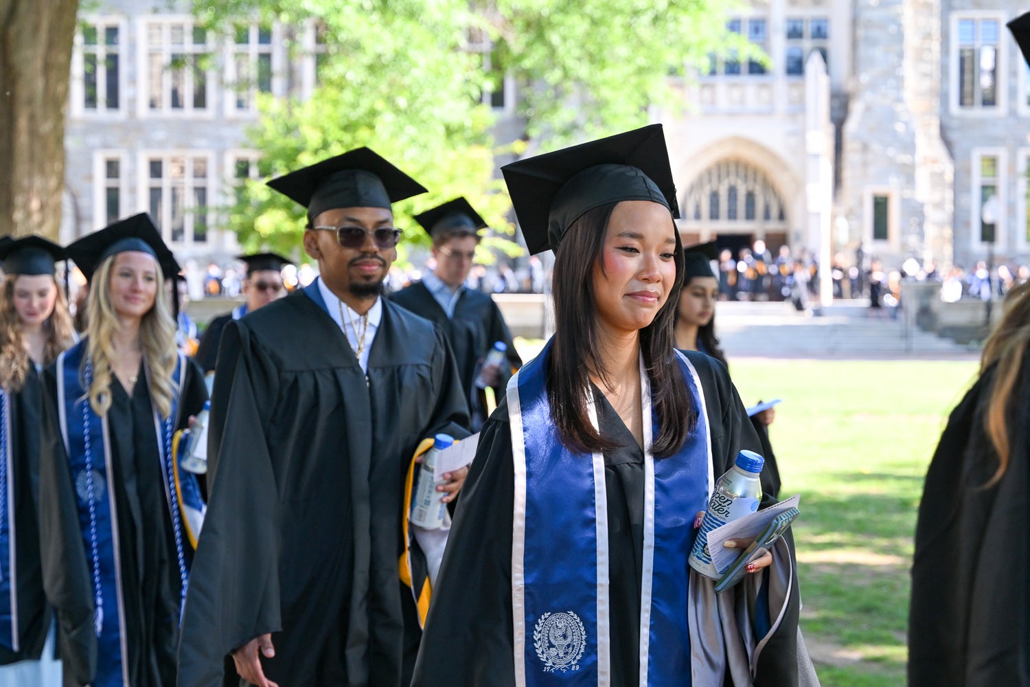 Graduates in commencement regalia process across Copley Lawn to the ceremony