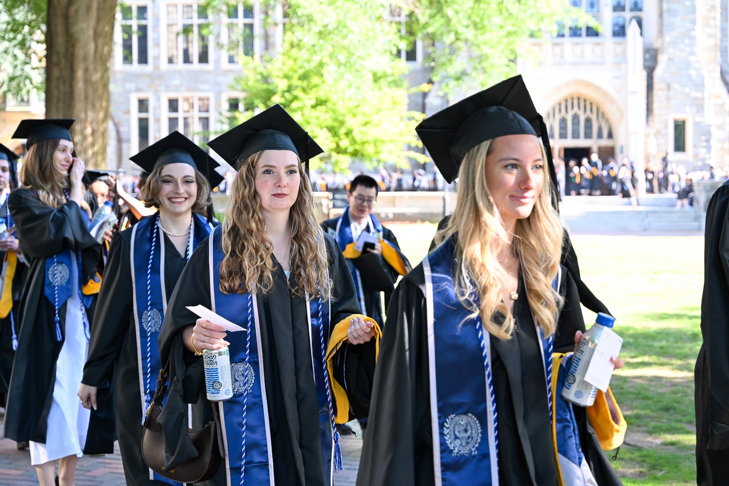 Graduates in commencement regalia process across Copley Lawn to the ceremony