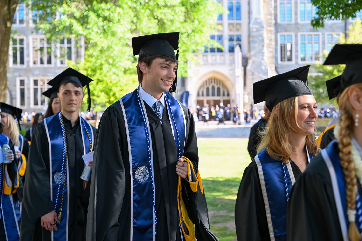 Graduates in commencement regalia process across Copley Lawn to the ceremony