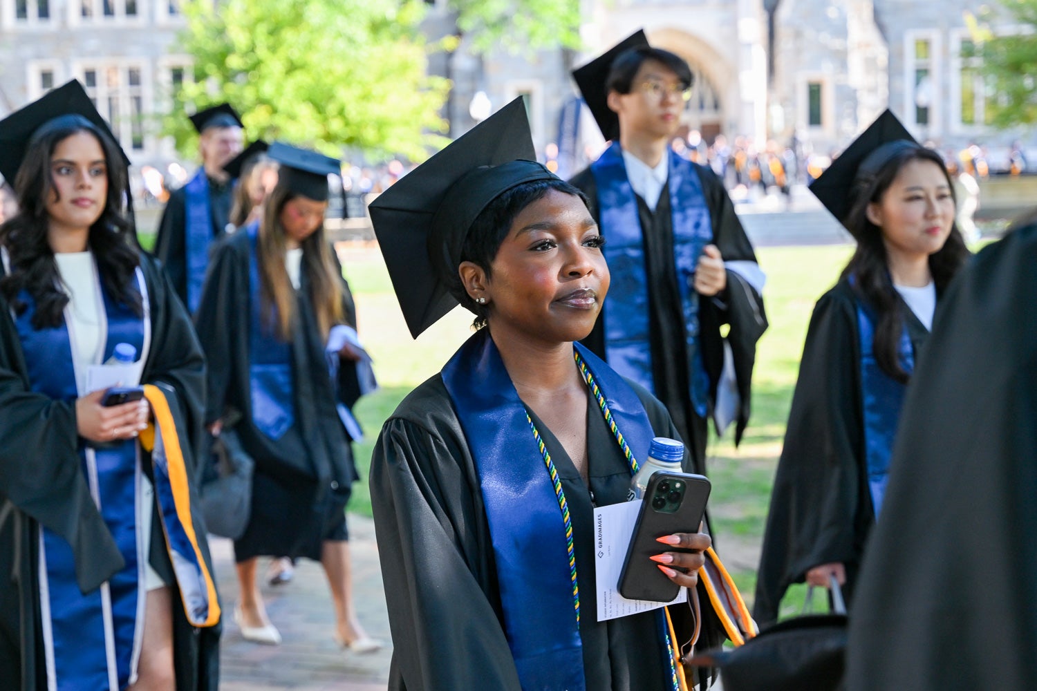 Graduates in commencement regalia process across Copley Lawn to the ceremony