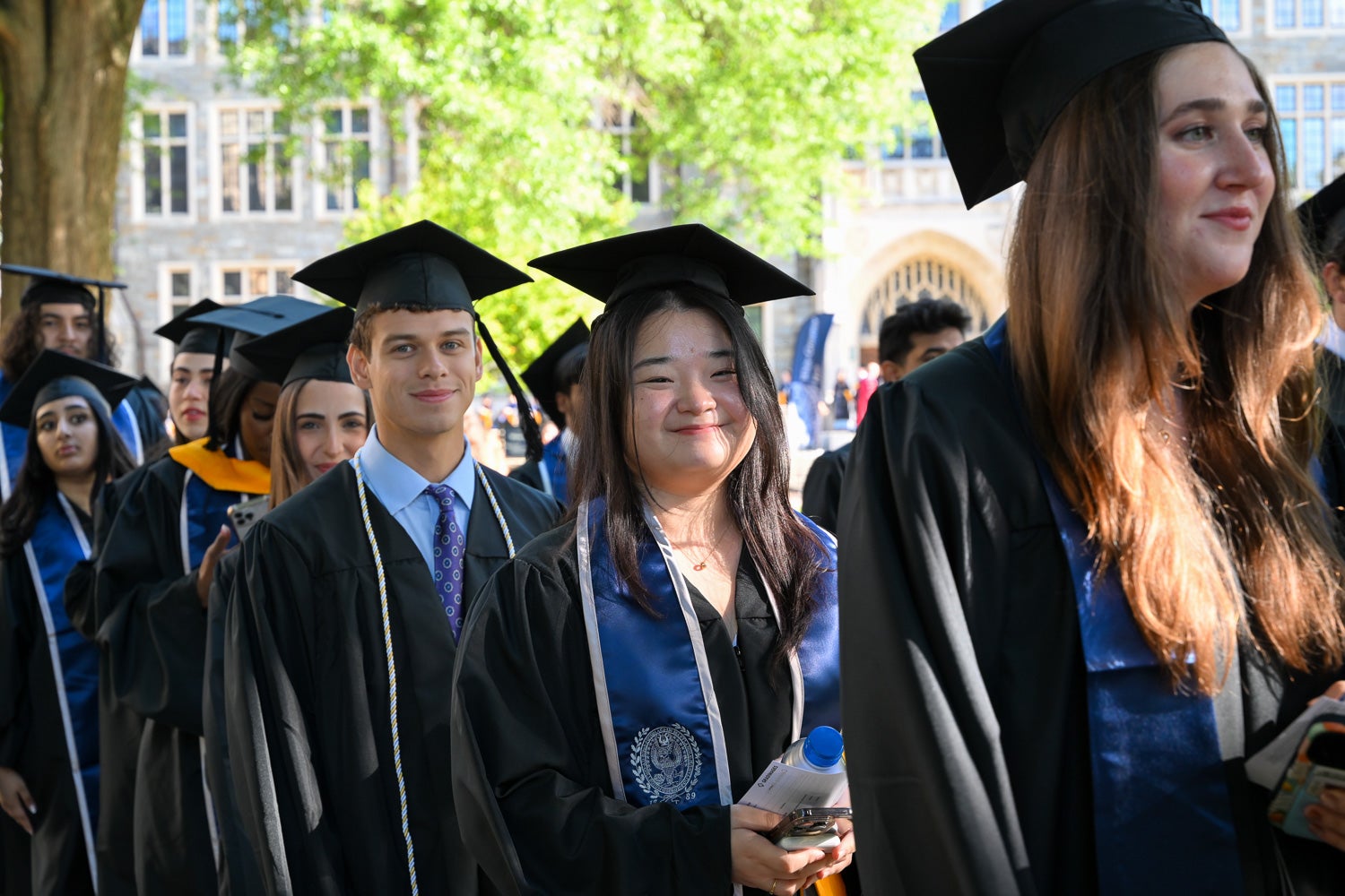 Graduates in commencement regalia process across Copley Lawn to the ceremony