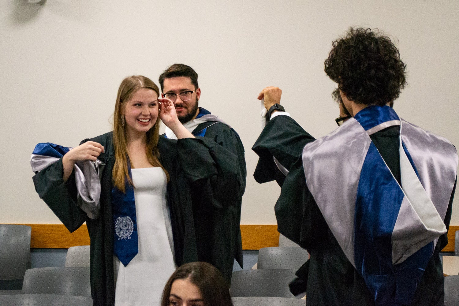 Graduates dressed in commencement regalia talk in the line-up room