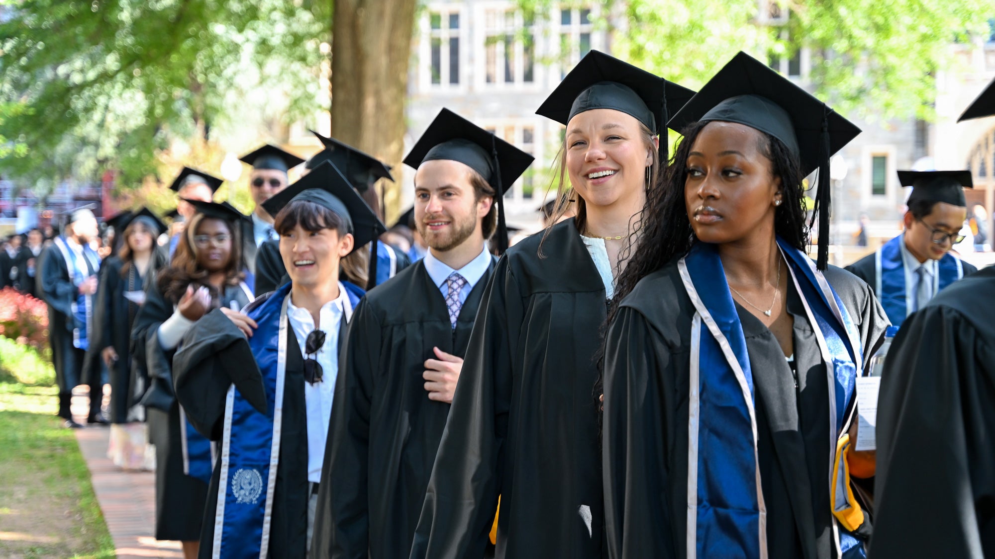 Graduates in commencement regalia process across Copley Lawn to the ceremony