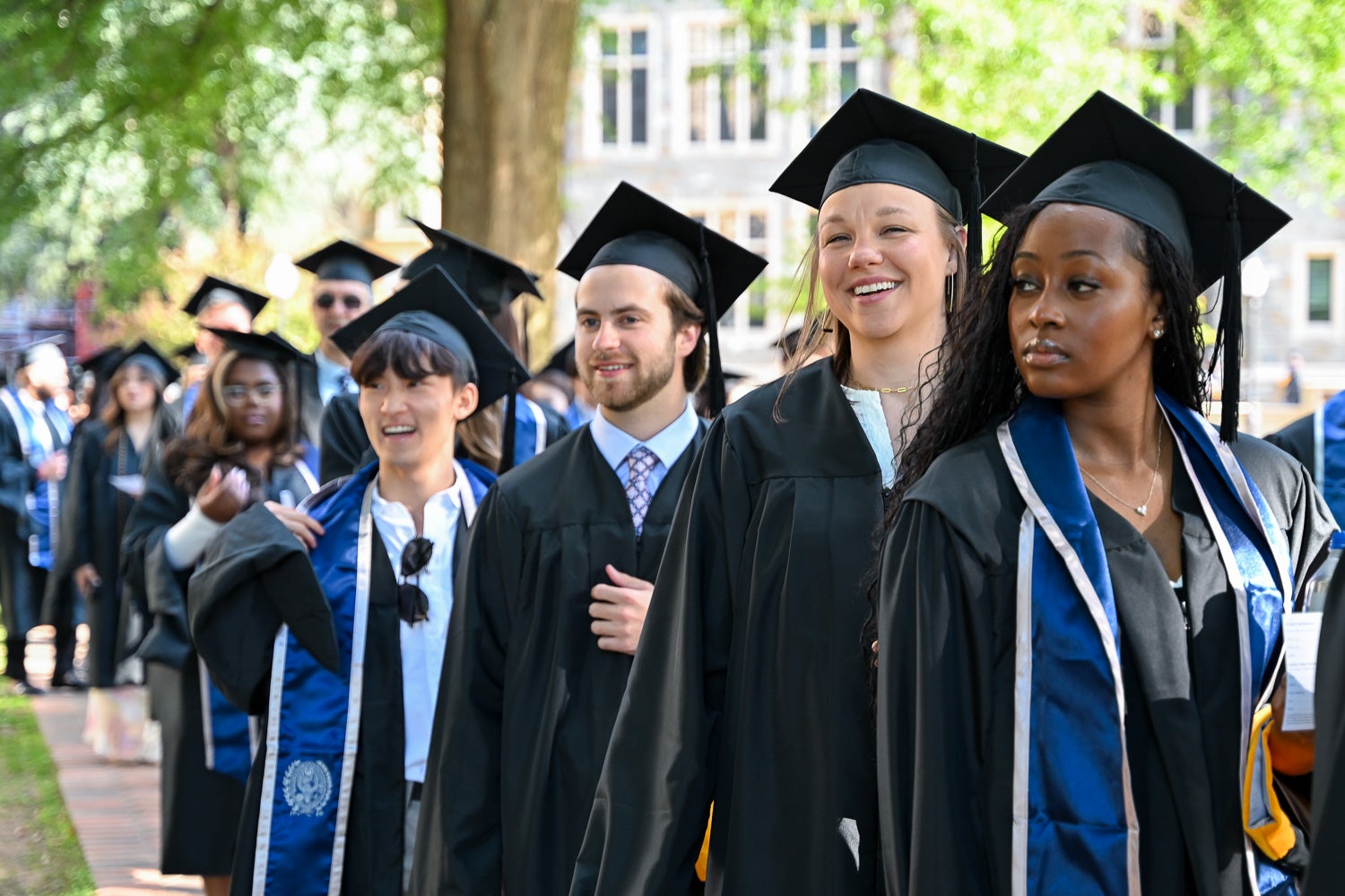 Graduates in commencement regalia process across Copley Lawn to the ceremony
